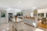 Kitchen featuring recessed lighting, stainless steel appliances, a breakfast bar, white cabinetry, and light stone counters