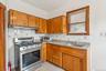 Kitchen featuring stainless steel range with gas cooktop, ventilation hood, tasteful backsplash, brown cabinets, and light tile patterned floors