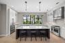 Matte-finished quartz countertops, a large center island with seating, tile backsplash, wood cabinetry with display shelving and pendant lighting crea