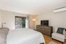 Bedroom featuring light wood-type flooring, access to exterior, a wall mounted air conditioner, and baseboard heating