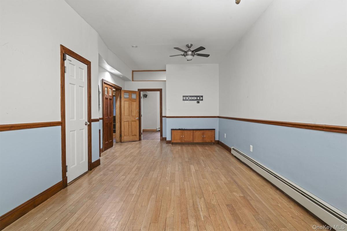 Empty room with a baseboard heating unit, light wood-style flooring, and ceiling fan