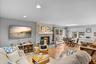 Living area with a skylight, a brick fireplace, wood finished floors, and recessed lighting