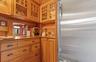 Kitchen featuring glass insert cabinets, a sink, wooden walls, brown cabinetry, and high end refrigerator