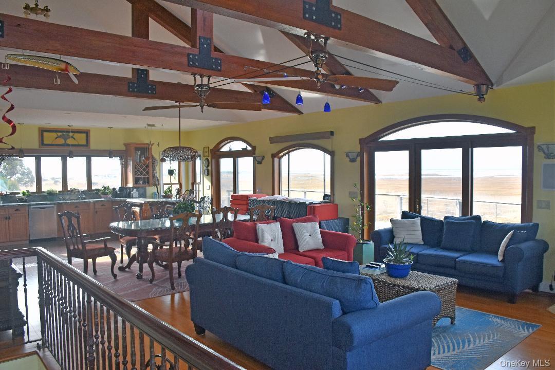 Living area featuring beamed ceiling, a ceiling fan, wood finished floors, and high vaulted ceiling