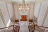 Grand two-story foyer featuring a large crystal chandelier, a double wooden entry door, a marble tile floor with dark accents, and twin curved stairca