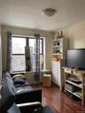 Living room with dark wood-style flooring, plenty of natural light, and radiator