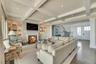 Living area with wood finished floors, beamed ceiling, a glass covered fireplace, stairs, and coffered ceiling