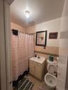Bathroom with tile walls, vanity, a shower with curtain, light tile patterned floors, and wainscoting