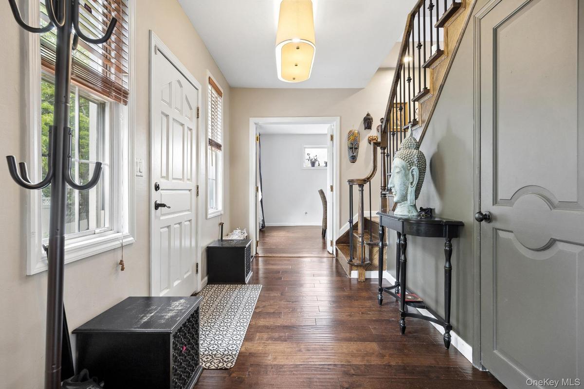 Elegant foyer showcasing gleaming hardwood floors, a striking staircase with detailed wood craftsmanship, and abundant natural light. A warm and invit