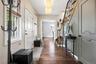 Elegant foyer showcasing gleaming hardwood floors, a striking staircase with detailed wood craftsmanship, and abundant natural light. A warm and invit