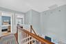 Hallway featuring an upstairs landing, wood finished floors, and wainscoting