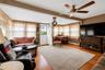 Spacious living area featuring wood-finish flooring, a ceiling fan with integrated lighting, and multiple windows