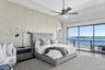 Bedroom featuring access to outside, a water view, vaulted ceiling, wallpapered walls, and a ceiling fan
