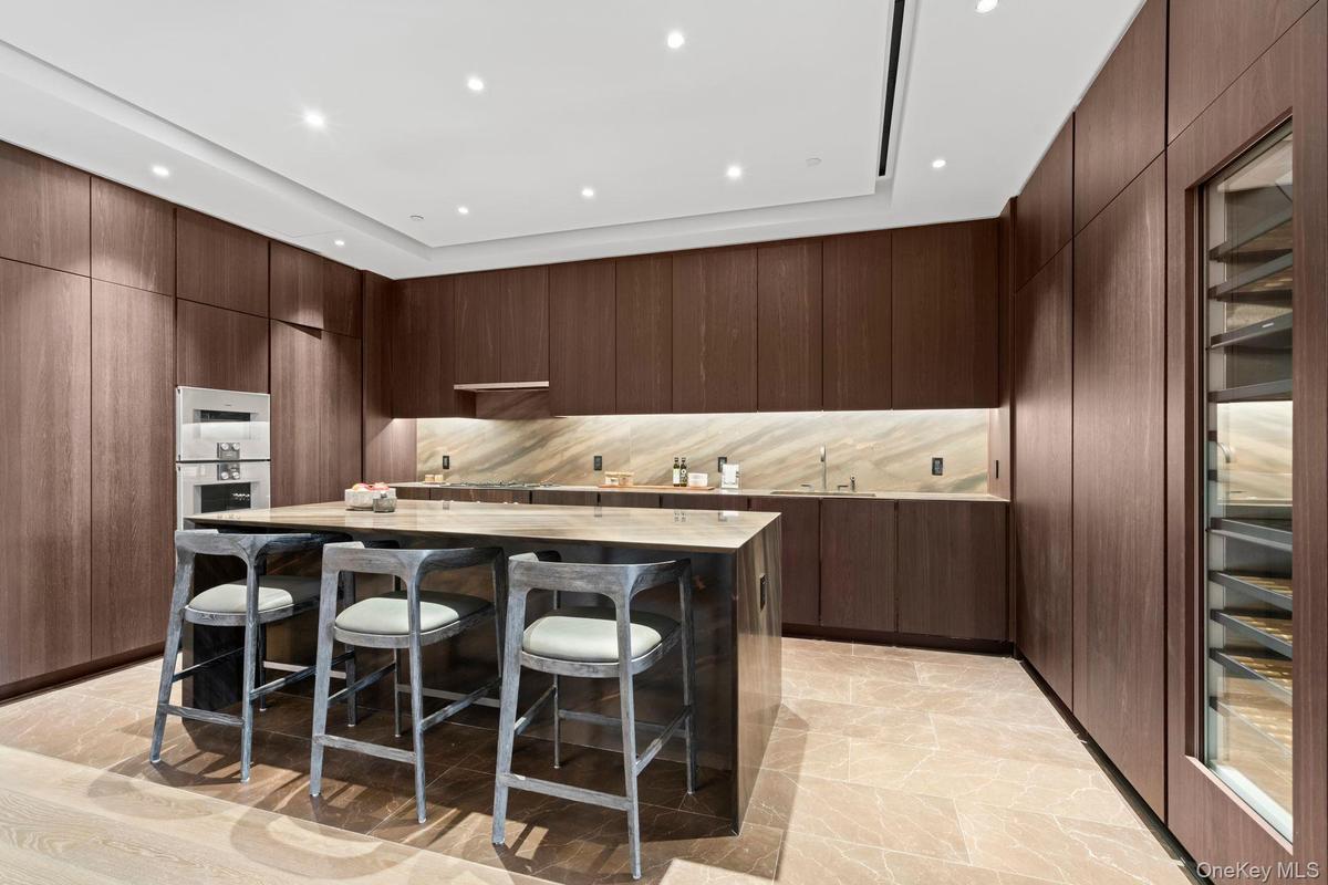 Kitchen with modern cabinets, a breakfast bar area, a center island, light countertops, and stainless steel double oven