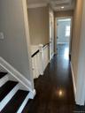 Corridor with dark wood-style flooring, ornamental molding, recessed lighting, and an upstairs landing