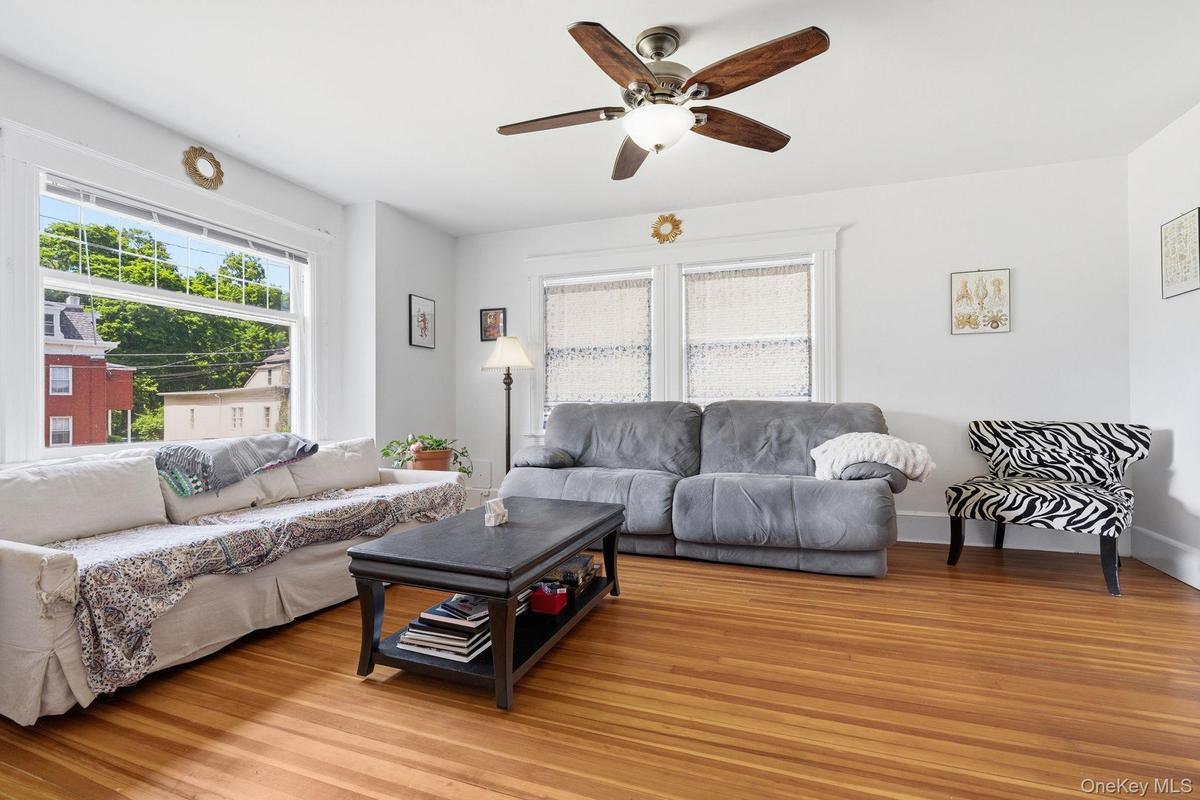 Sunlight pours through expansive windows, filling this spacious living room with warmth and natural beauty.