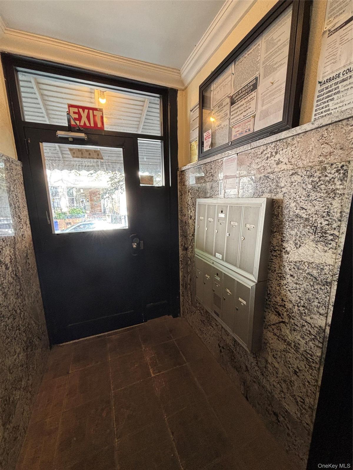 Entryway featuring multi-unit mailboxes, dark-toned flooring, and patterned wall finishes