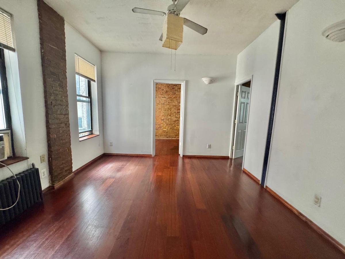 Unfurnished living room with radiator heating unit, wood finished floors, and a ceiling fan