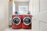 Laundry Room – Spacious laundry room featuring side-by-side front-loading washer and dryer, additional storage, and a window that fills the space with