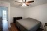 Wood-finish flooring, white walls, and a ceiling fan with integrated lighting