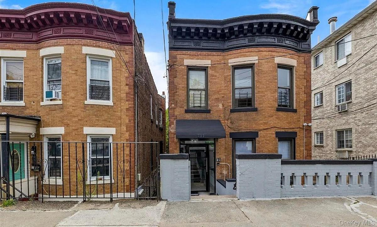 Brick facade with bay window, black accent trim, street-level entry, and a decorative perimeter wall