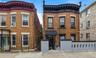 Brick facade with bay window, black accent trim, street-level entry, and a decorative perimeter wall
