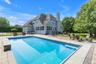 Spacious backyard featuring a rectangular, heated in-ground pool, paver patio, black metal fencing