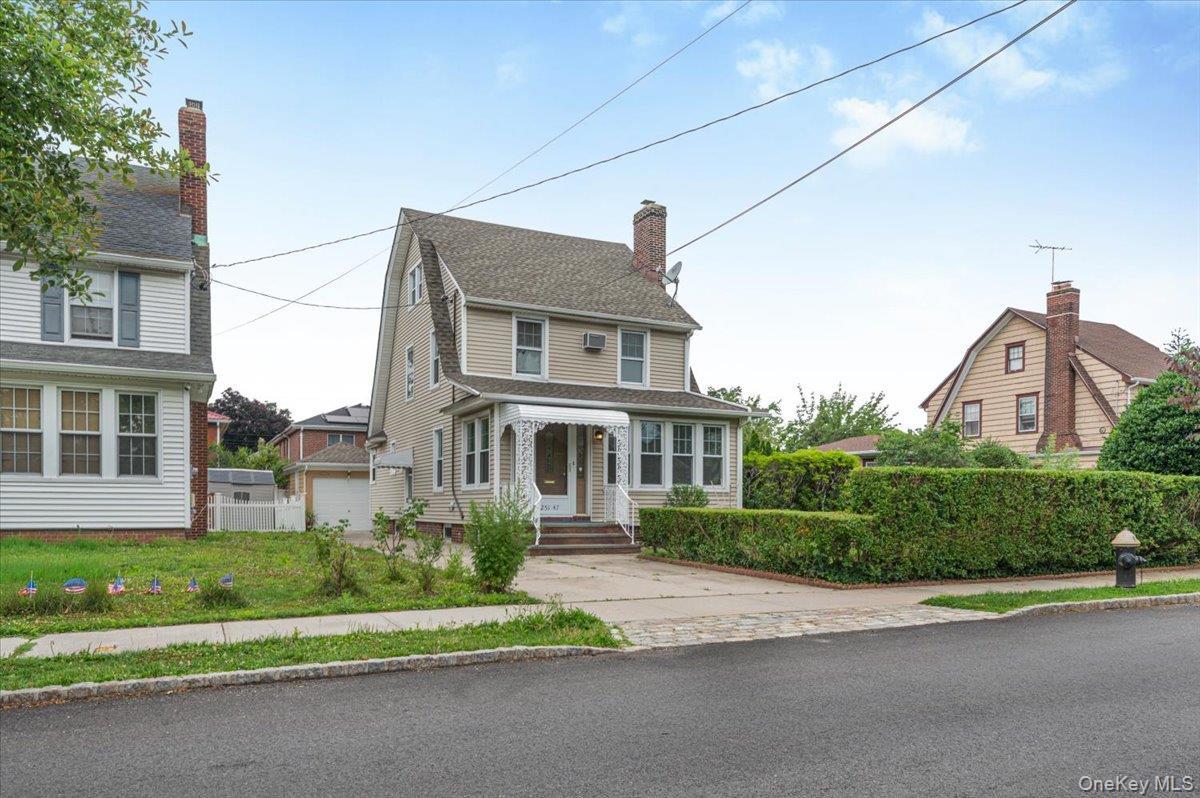 Traditional-style residence featuring light beige siding and a prominent Gambrel roofline
