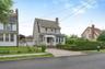 Traditional-style residence featuring light beige siding and a prominent Gambrel roofline