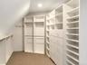Spacious closet with light colored carpet and lofted ceiling