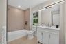 Bathroom featuring a white tub, textured beige tile surround with recessed niche, and a white vanity with an undermount sink and chrome fixtures