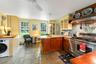 Kitchen featuring range with two ovens, washer / dryer,microwave, custom exhaust hood, and a peninsula