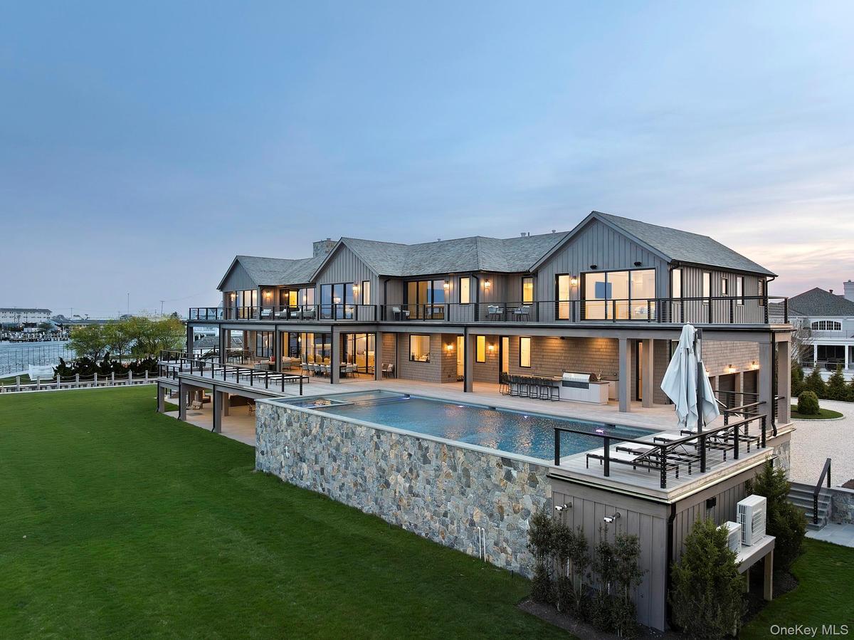 Back of property at dusk with a balcony, a yard, an outdoor living space, an outdoor pool, and a patio area