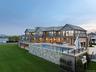 Back of property at dusk with a balcony, a yard, an outdoor living space, an outdoor pool, and a patio area