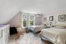 Bedroom with a wall mounted AC, radiator heating unit, vaulted ceiling, and light wood-style floors