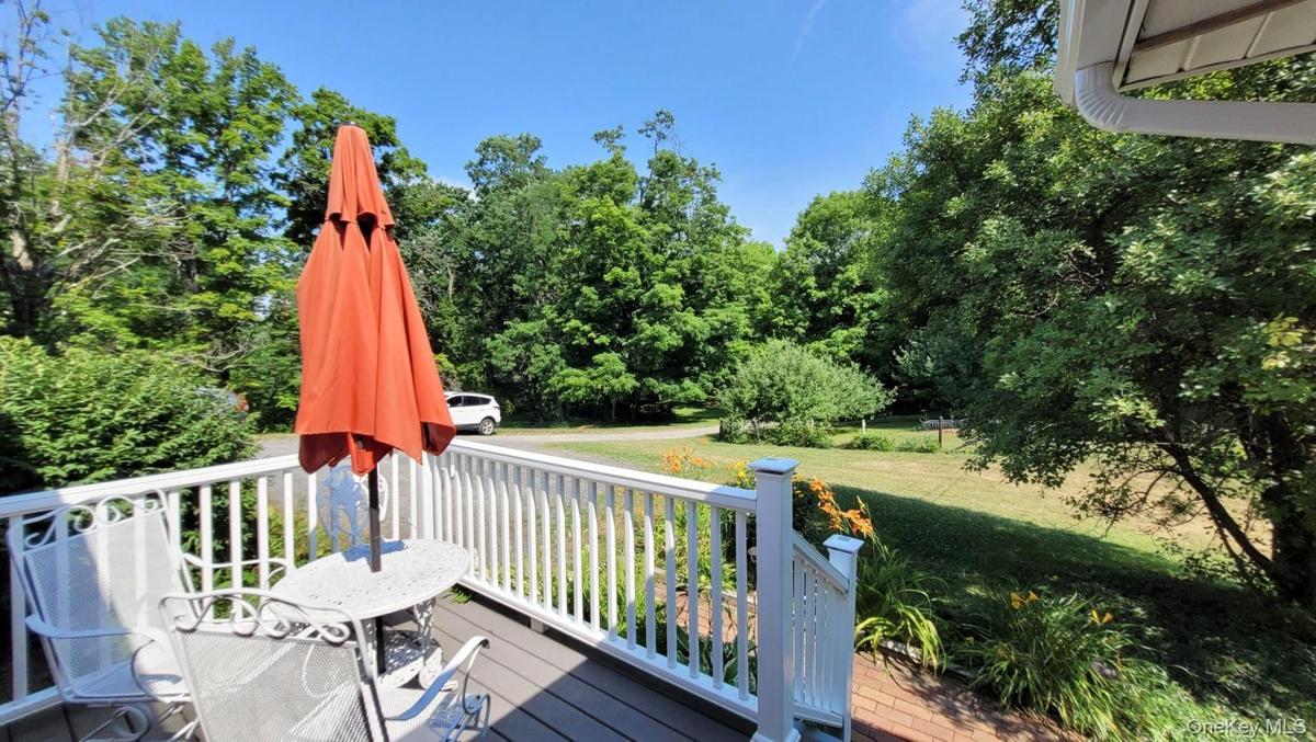 Outdoor deck with composite decking and white railings, offering views of a landscaped yard with mature trees