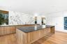 Kitchen with modern cabinets, a large island, beverage cooler, white cabinets, and dark stone counters