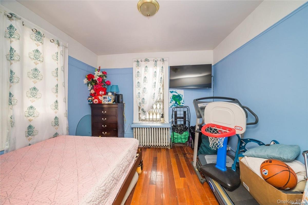 Bedroom with wood-type flooring and radiator heating unit