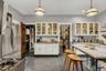 Kitchen with white cabinets, appliances with stainless steel finishes, glass insert cabinets, open shelves, and hanging light fixtures