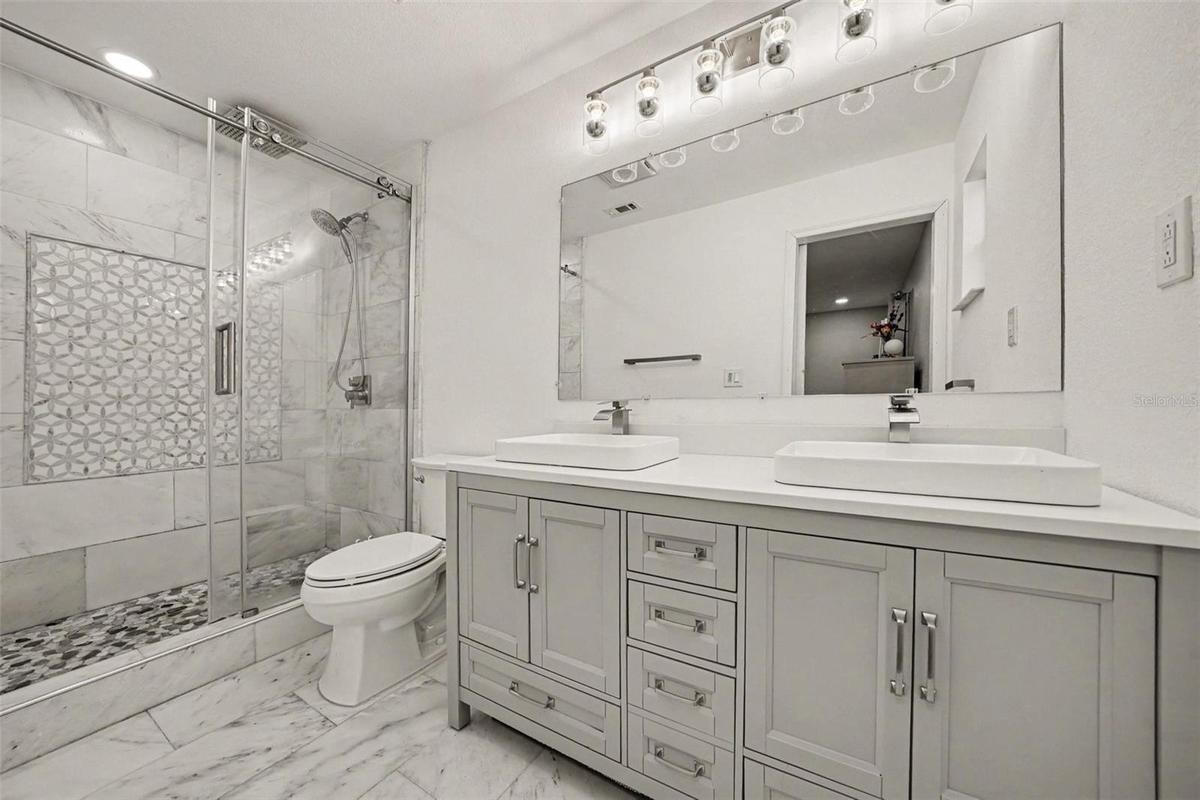 Primary Bath w/Marble tiled walk-in shower, marble tiled flooring and vanity w/ double sinks