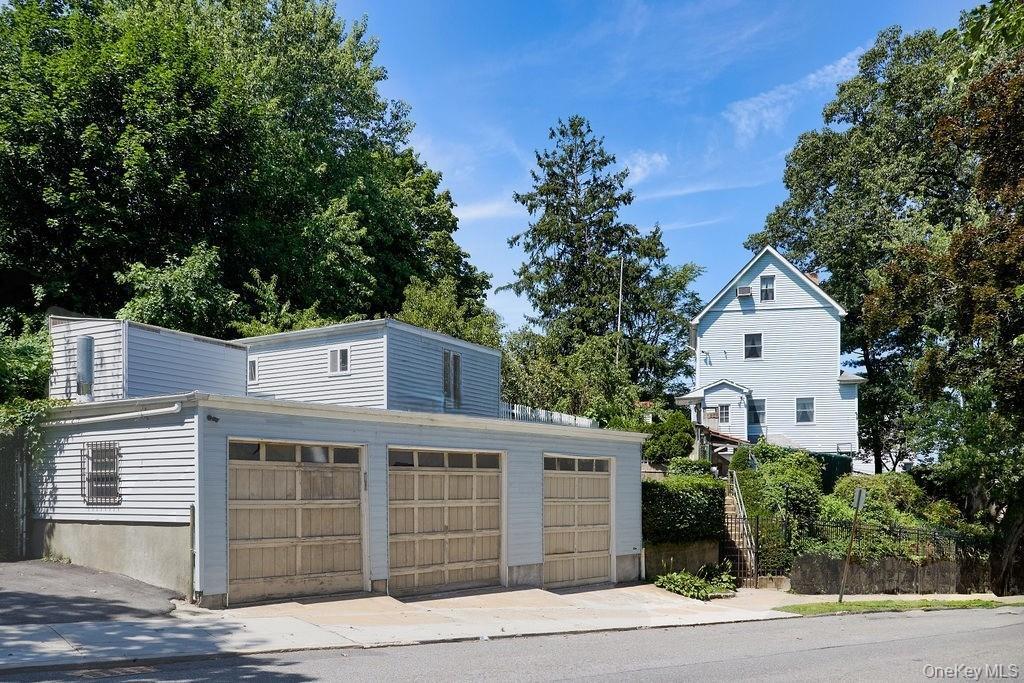 View from the side street. 3 car garage, with two rooms above it. Can be an office or additional storage space.