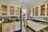 Butlers Pantry between formal dining room and kitchen, featuring cream cabinetry, stainless steel sink