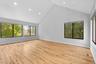 Empty room featuring high vaulted ceiling, wood finished floors, baseboards, visible vents, and recessed lighting