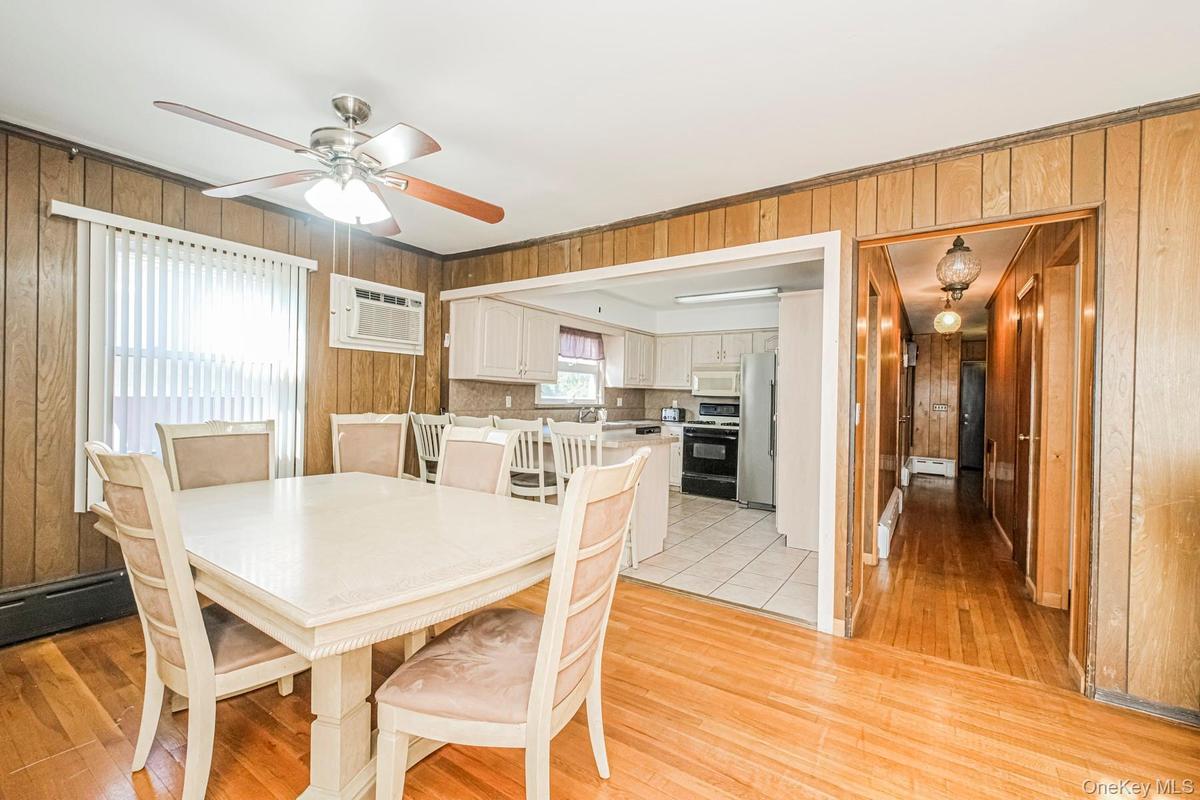 Hardwood flooring defines this dining space, featuring a ceiling fan with integrated lighting