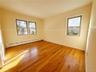 Spare room featuring a healthy amount of sunlight, baseboards, baseboard heating, and wood finished floors