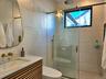 Bathroom featuring vanity, backsplash, toilet, a shower stall, and tile walls