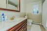 Bathroom with vanity, tile patterned flooring, toilet, baseboard heating, and tile walls