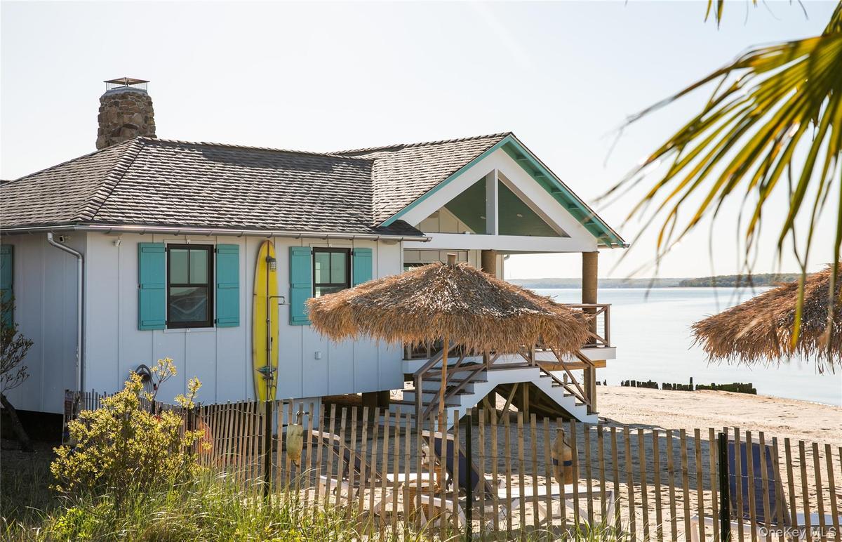 View of front of home featuring a fenced front yard, stairs, board and batten siding, a chimney, and a water view