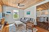 Living area featuring a wood-panel ceiling, ceiling fan with integrated lighting, and a window providing natural light