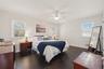 Bedroom with multiple windows, ceiling fan, and dark hardwood / wood-style flooring